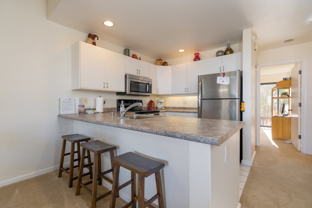 2777 South Kihei Road, Unit L204 Kihei, HI 96753 - Photo 9 of 30 a kitchen with kitchen island granite countertop a table chairs microwave and refrigerator