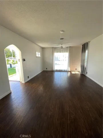 a view of an empty room with window and wooden floor