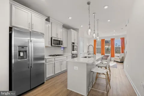 a kitchen with stainless steel appliances a refrigerator a stove a sink and white cabinets with wooden floor