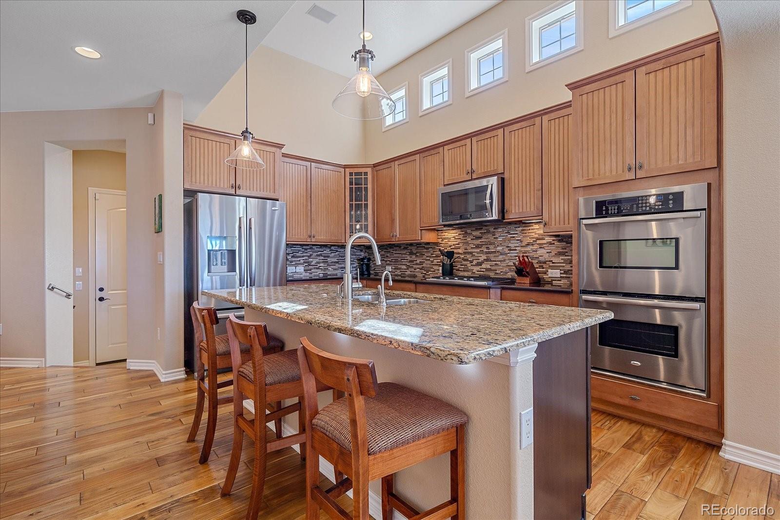 9317 Viaggio Way Highlands Ranch, CO 80126 - Photo 8 of 50 a kitchen with stainless steel appliances granite countertop a kitchen island a stove a refrigerator a sink and a cabinets