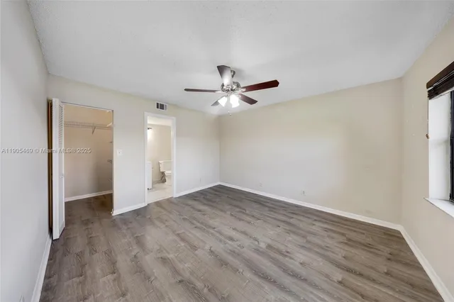 an empty room with wooden floor and ceiling fan
