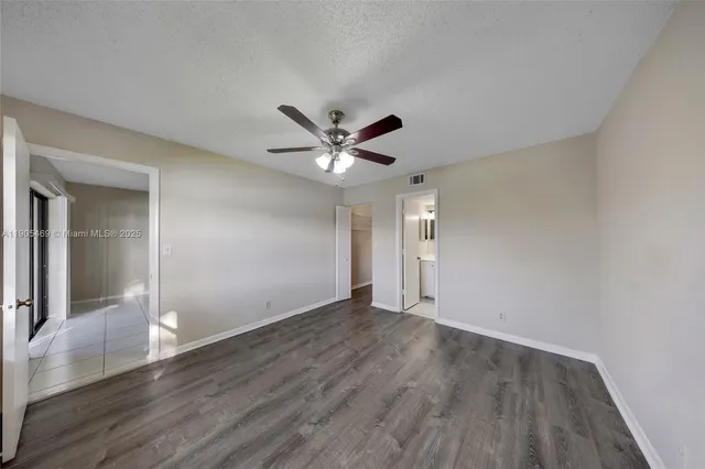 an empty room with wooden floor and a ceiling fan
