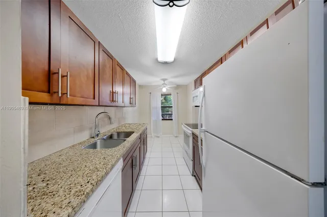 a kitchen with stainless steel appliances granite countertop a sink refrigerator and cabinets