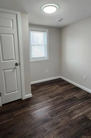 an empty room with wooden floor and window
