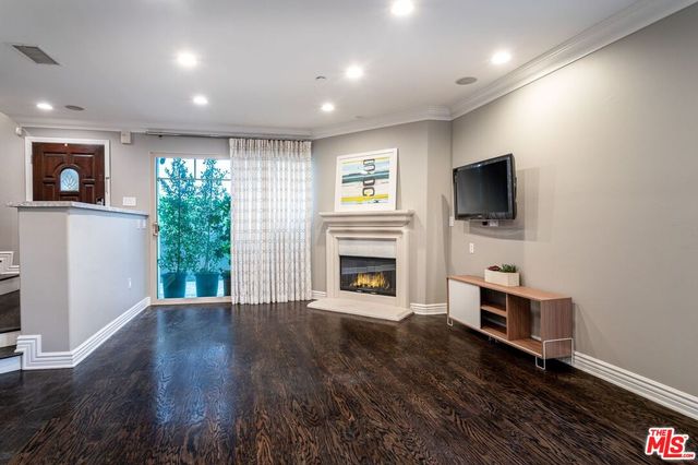 a view of a livingroom with a fireplace a window and wooden floor