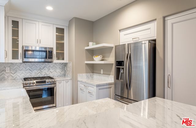 a kitchen with stainless steel appliances granite countertop a refrigerator and a stove top oven