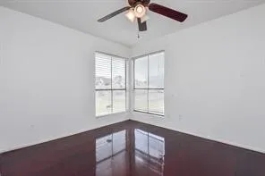 an empty room with chandelier fan and windows