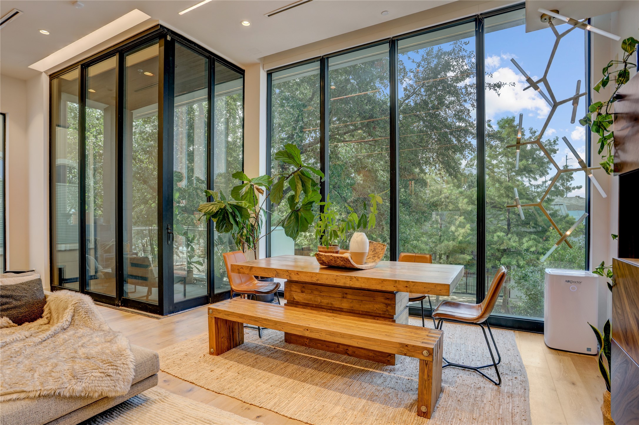 1807 Indiana Street Houston, TX 77006 - Photo 11 of 35 Dining Area & Balcony: Elegant dining space defined by soaring floor-to-ceiling windows and a massive sliding glass wall that opens directly onto a covered private balcony, offering serene treetop views.