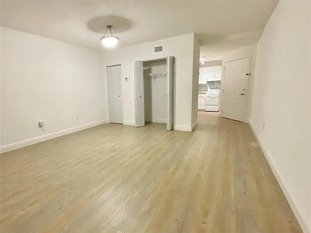 a view of an empty room and a kitchen