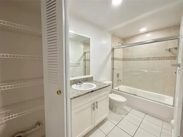 a bathroom with a granite countertop sink a toilet and shower