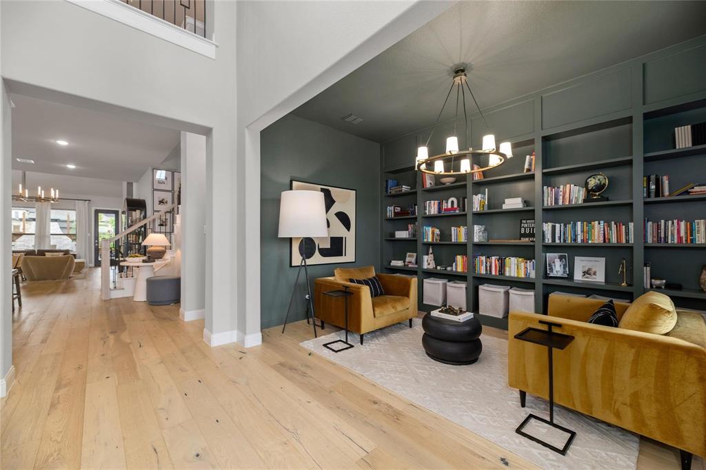 2262 Poppyvine Road Frisco, TX 75033 - Photo 12 of 40 Built-in shelving, wood-finish flooring, two-story ceiling, and a contemporary chandelier