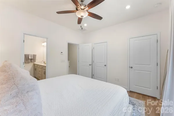 a bedroom with a large bed and a chandelier fan
