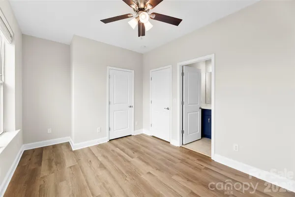 a view of empty room with wooden floor and fan