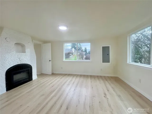 an empty room with windows and fireplace