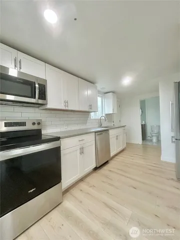 a large kitchen with stainless steel appliances granite countertop a stove a sink and a microwave