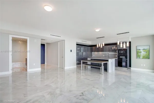 a kitchen with stainless steel appliances kitchen island granite countertop a refrigerator oven a sink dishwasher and white cabinets with wooden floor