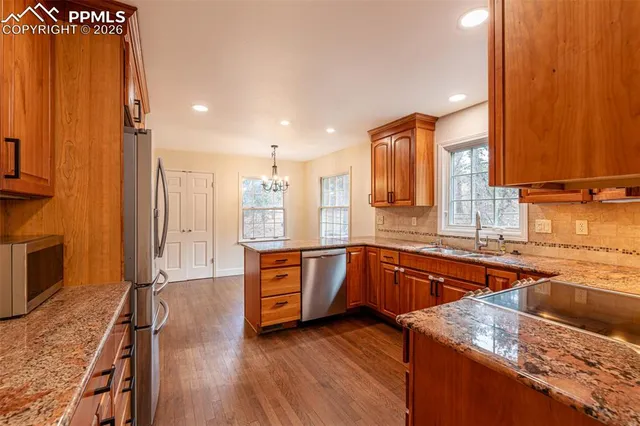 a kitchen with stainless steel appliances granite countertop wooden cabinets a sink and dishwasher a stove with wooden floor