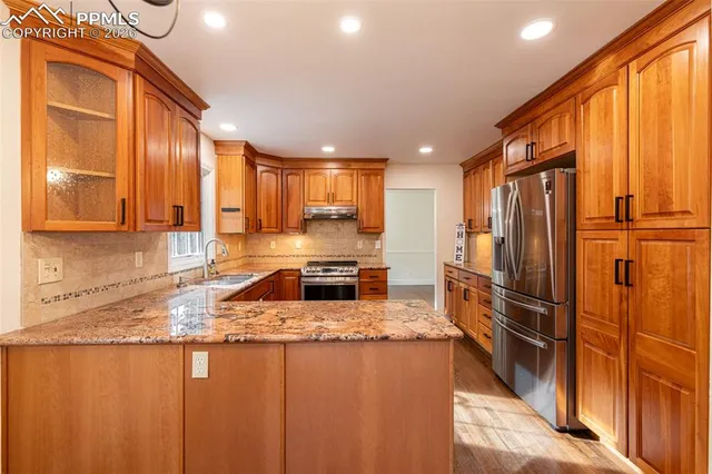 a kitchen with stainless steel appliances granite countertop a refrigerator and a sink