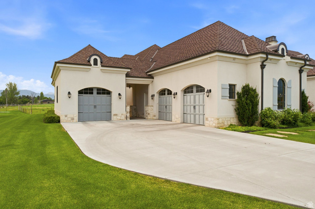 71 Farm Road Midway, UT 84049 - Photo 92 of 92 Stucco exterior featuring multiple arched garage doors, a curved concrete driveway, and a shingle roof
