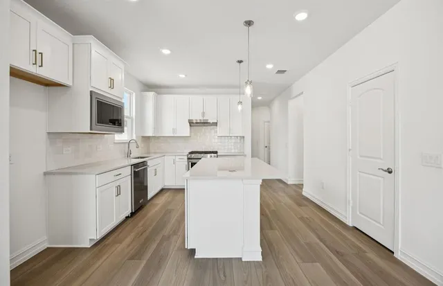 a large kitchen with cabinets wooden floor and stainless steel appliances