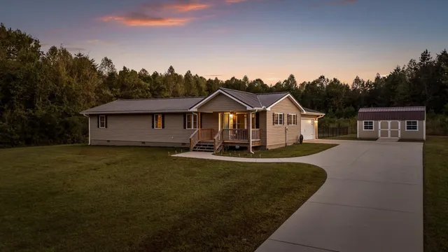 a front view of a house with a garden and trees