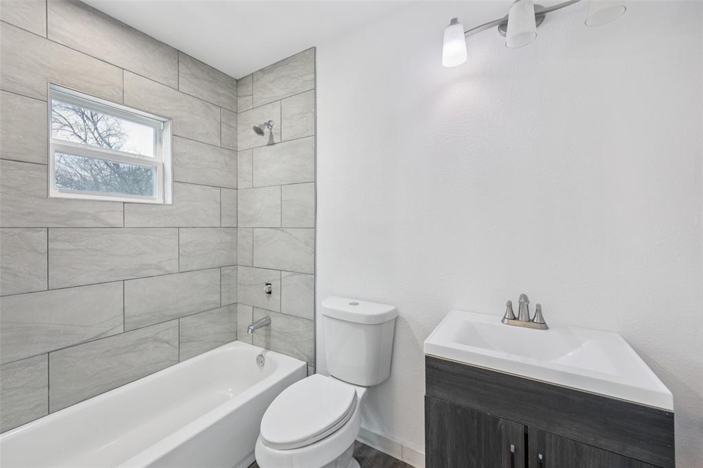 3847 Stalcup Road Fort Worth, TX 76119 - Photo 19 of 30 a bathroom with a toilet a sink a mirror and a bathtub