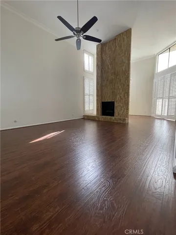 an empty room with wooden floor fireplace and windows