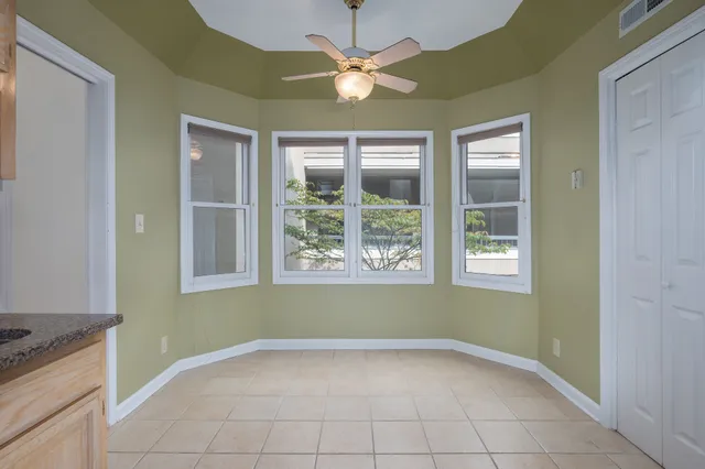 an empty room with chandelier fan and windows