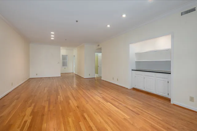 a view of empty room with wooden floor and fan