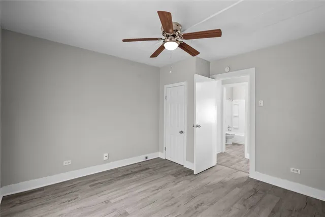 an empty room with wooden floor a ceiling fan and closet area