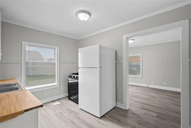 an empty room with wooden floor and a refrigerator