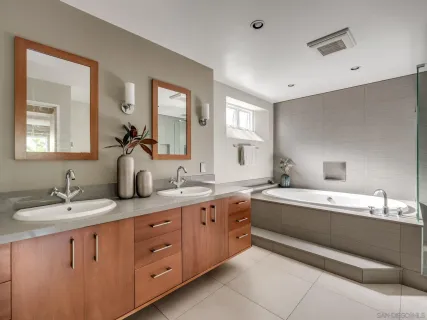 a bathroom with a granite countertop double vanity sink and mirror with bathtub
