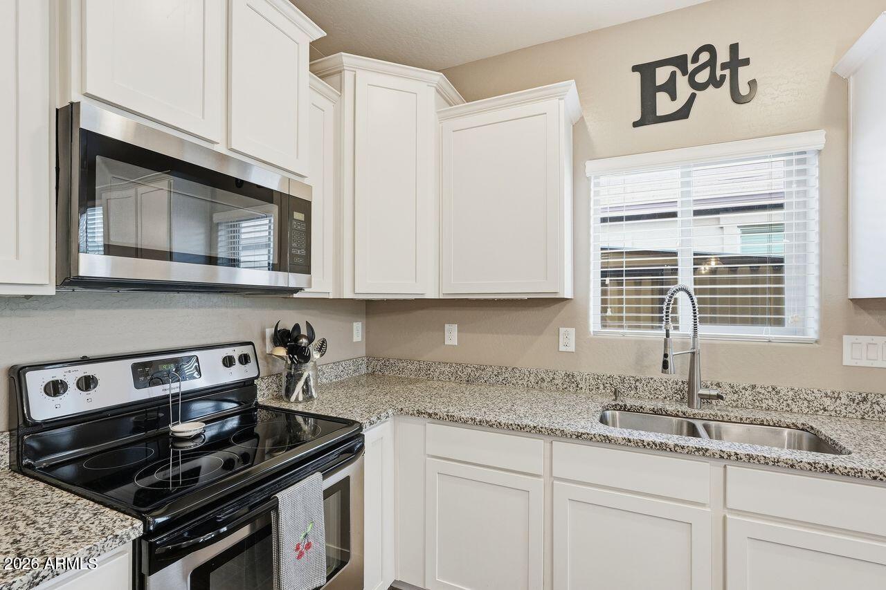 23602 West Ripple Road Buckeye, AZ 85326 - Photo 16 of 38 a kitchen with granite countertop a sink stove and cabinets