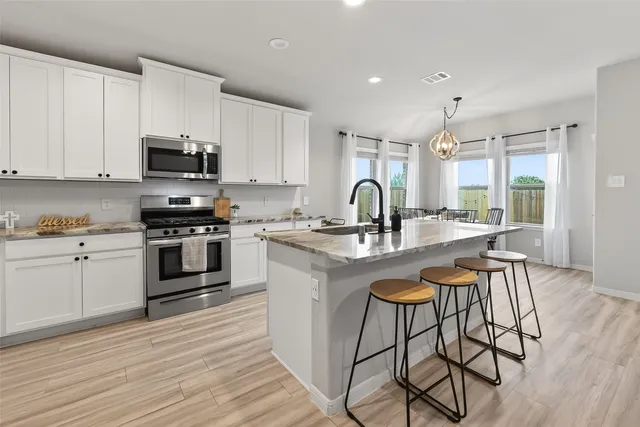 a kitchen with stainless steel appliances granite countertop a stove a sink and a microwave