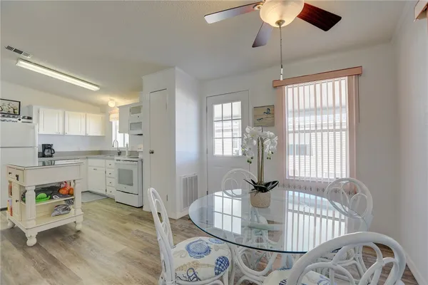 a open dining room with wooden floor a chandelier a wooden table and chairs