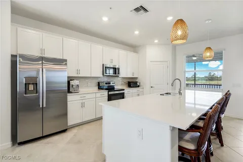 a kitchen with refrigerator a sink a stove and a chandelier