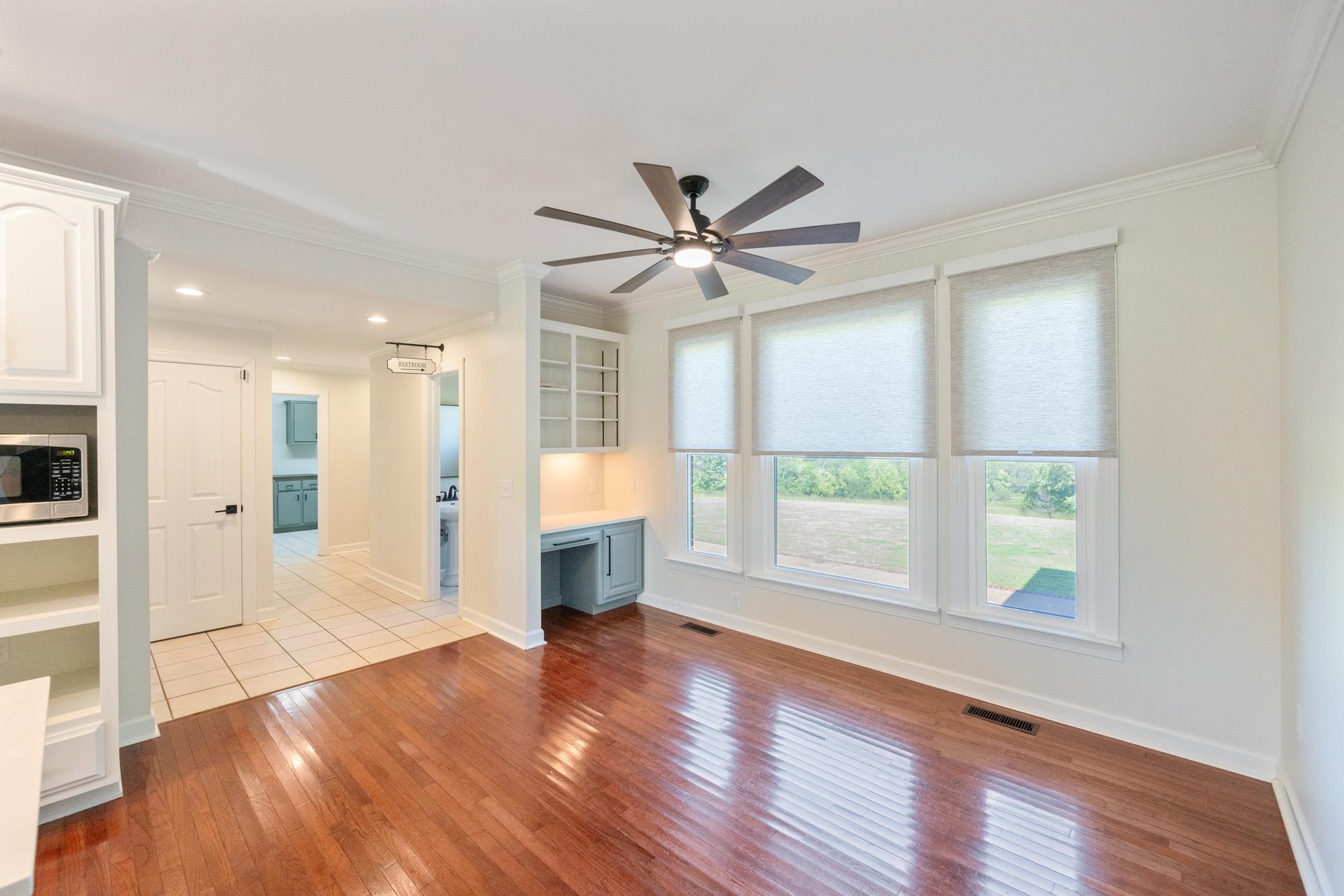 599 DT Vise Loop Parsons, TN 38363 - Photo 12 of 40 Unfurnished living room featuring built in desk, crown molding, light wood finished floors, and ceiling fan