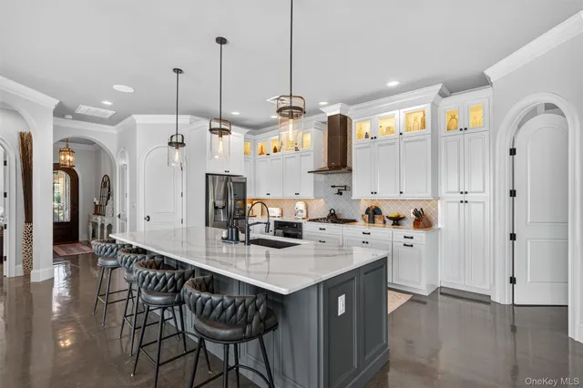 a kitchen with stainless steel appliances granite countertop a sink a stove a refrigerator a center island and chairs