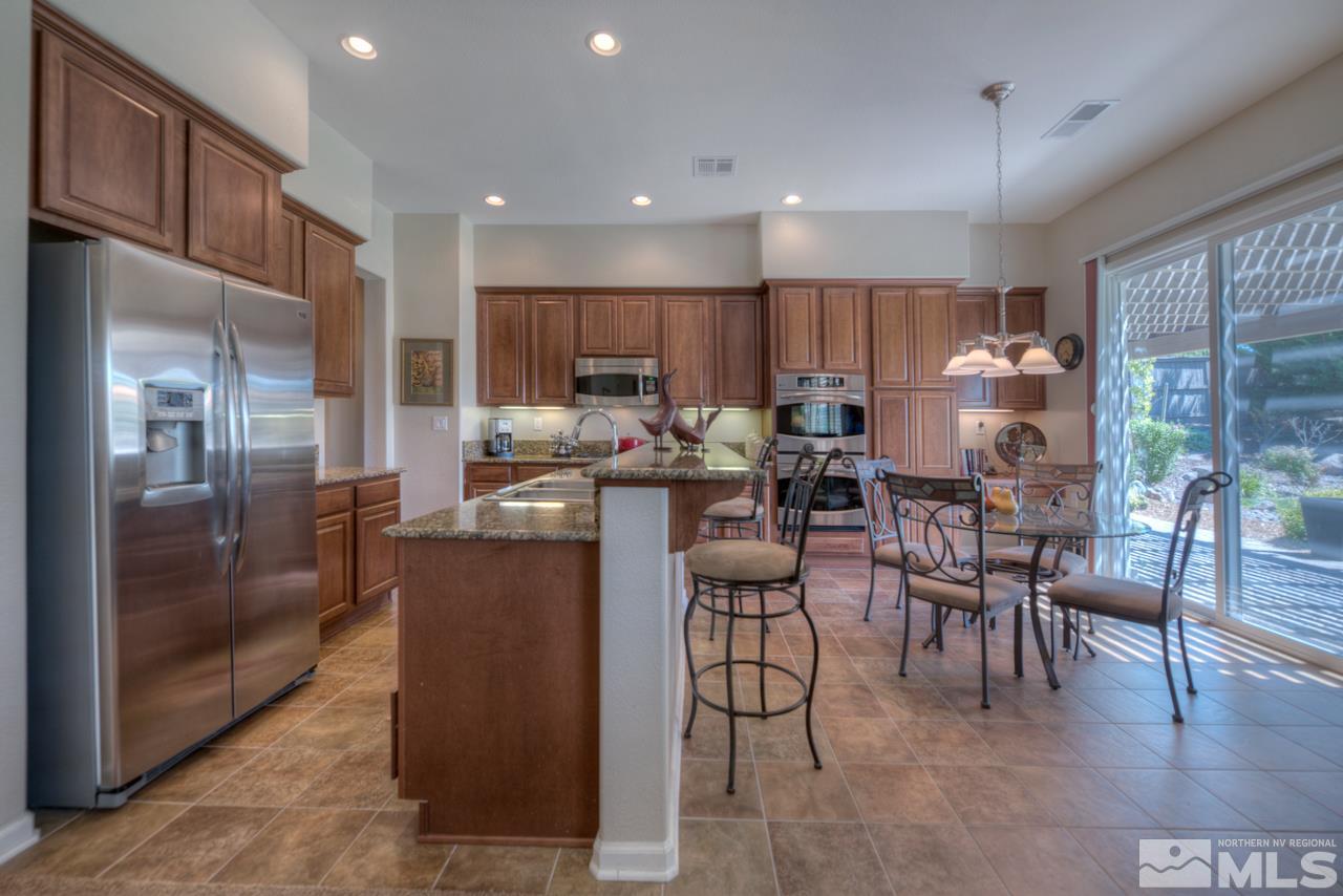 750 Sienna Station Way Reno, NV 89512 - Photo 8 of 21 a kitchen with stainless steel appliances kitchen island granite countertop a refrigerator a stove a dining table and chairs