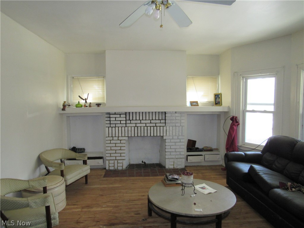 863 Eddy Road Cleveland, OH 44108 - Photo 10 of 28 Living area featuring a painted brick fireplace, wood flooring, and a ceiling fan. Unit 1