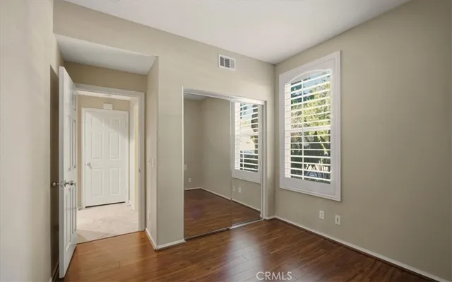 an empty room with wooden floor closet and windows