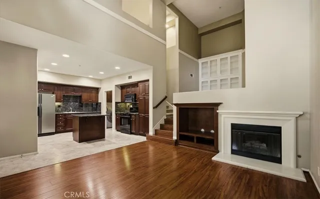 a view of a livingroom with a fireplace wooden floor and kitchen view