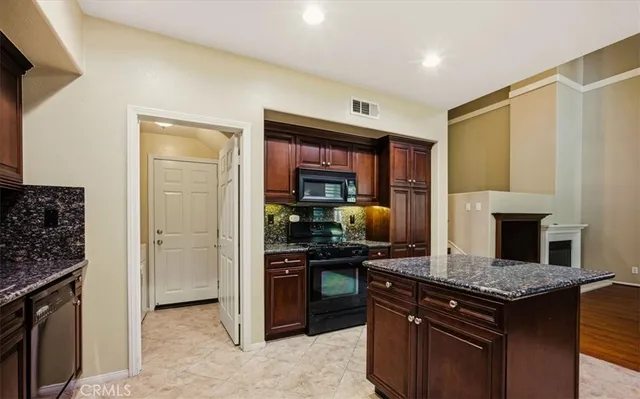 a kitchen with stainless steel appliances granite countertop a stove top oven a sink and a refrigerator