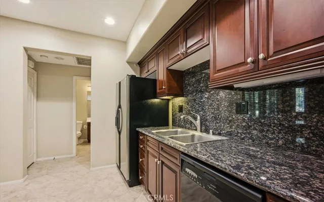 a kitchen with granite countertop a sink a stove and refrigerator