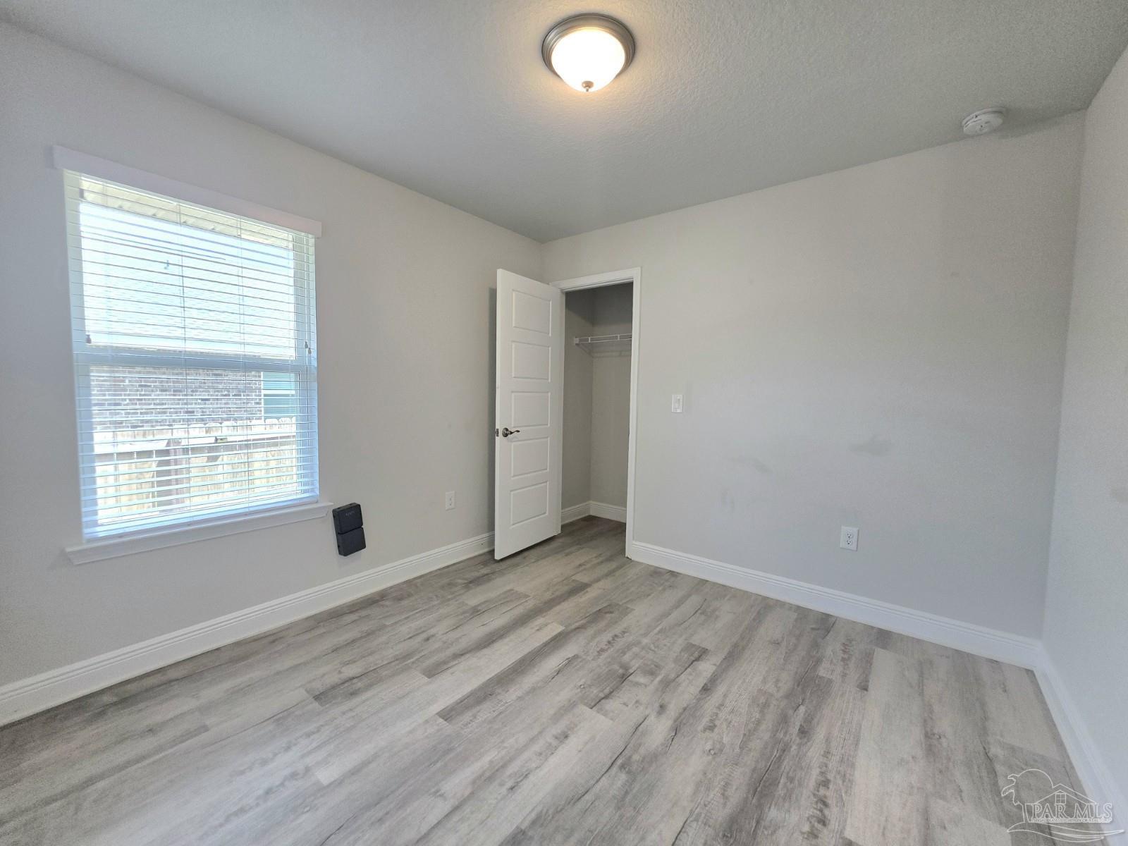 5031 Firstmate Way Pensacola, FL 32526 - Photo 16 of 27 an empty room with wooden floor and windows