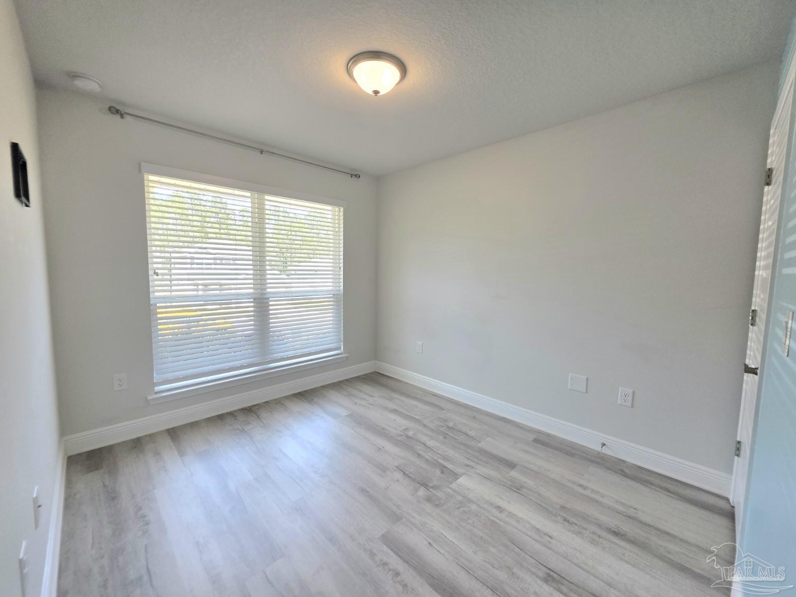 5031 Firstmate Way Pensacola, FL 32526 - Photo 20 of 27 an empty room with wooden floor and windows