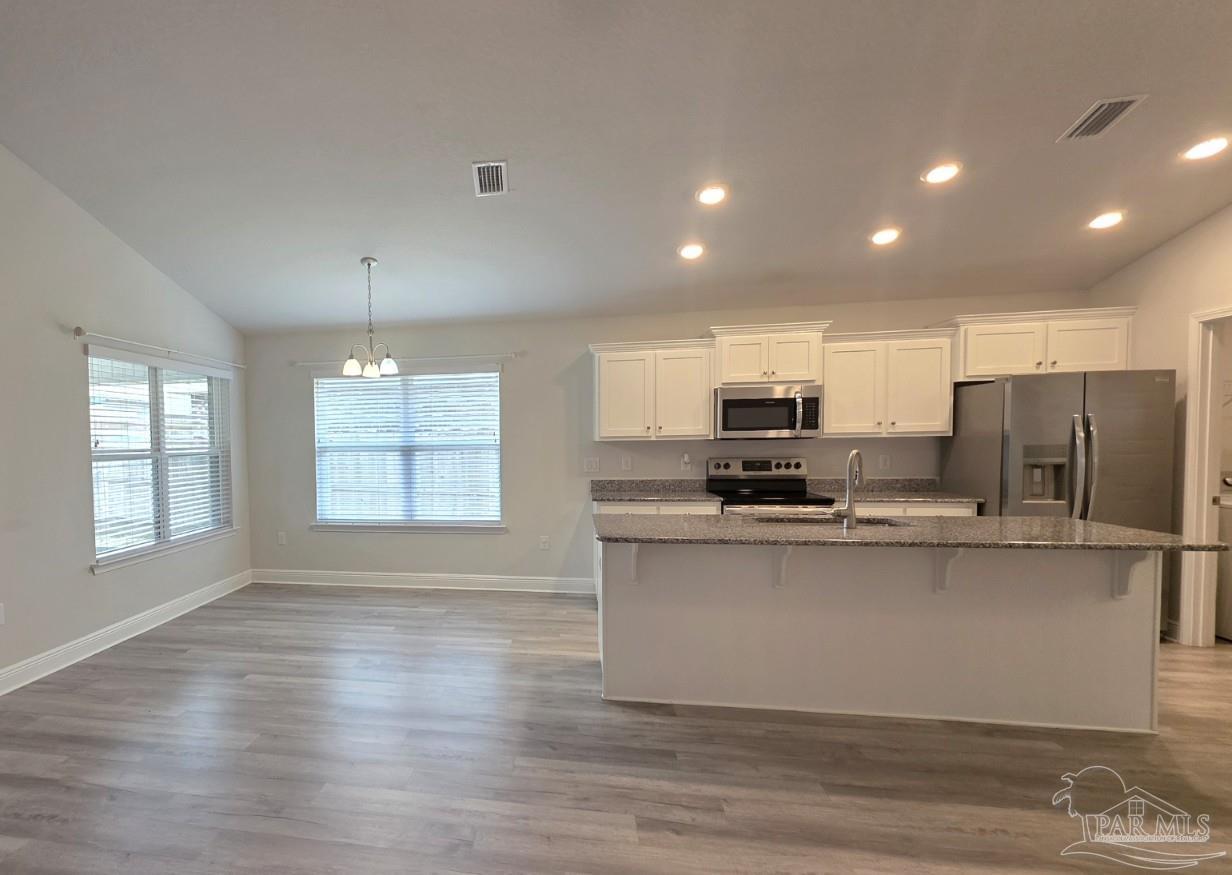 5031 Firstmate Way Pensacola, FL 32526 - Photo 7 of 27 a kitchen with stainless steel appliances granite countertop a sink a stove a refrigerator cabinets and a wooden floor