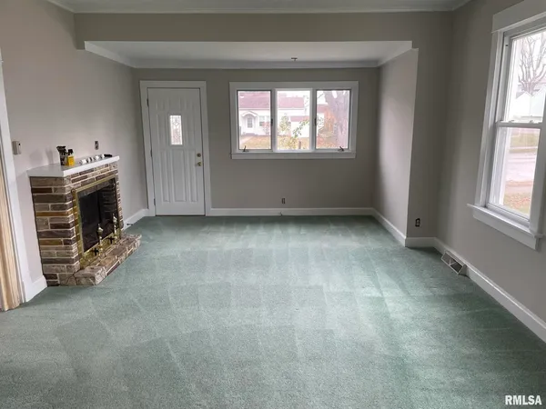 an empty room with windows cabinet and fireplace