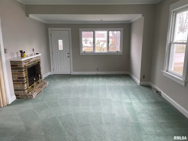 an empty room with windows cabinet and fireplace