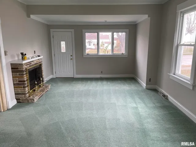an empty room with windows cabinet and fireplace